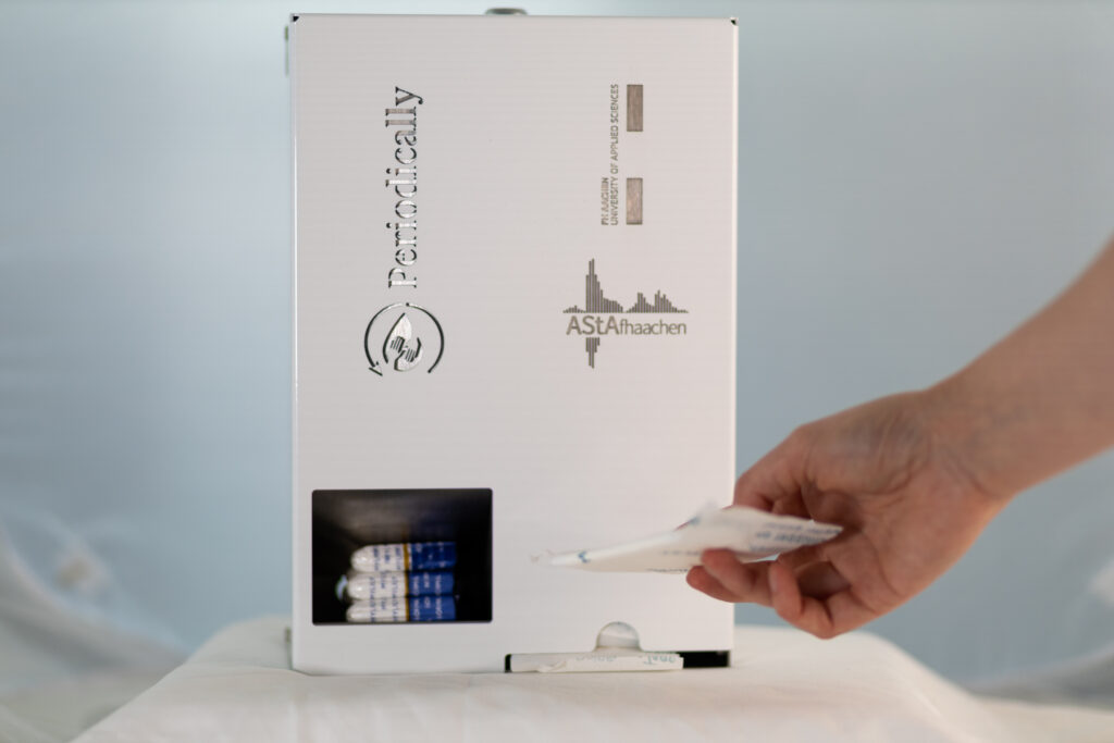 Ein weißer Periodenprodukt-Spender, aus dem Binden und Tampons entnommen werden.